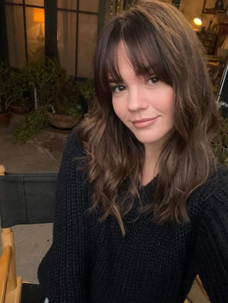 a woman sitting at a table with food in front of her and looking into the camera