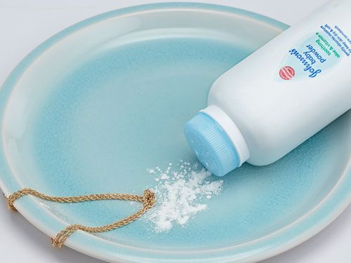 a bottle of baby powder sitting on top of a blue plate with a chain attached to it