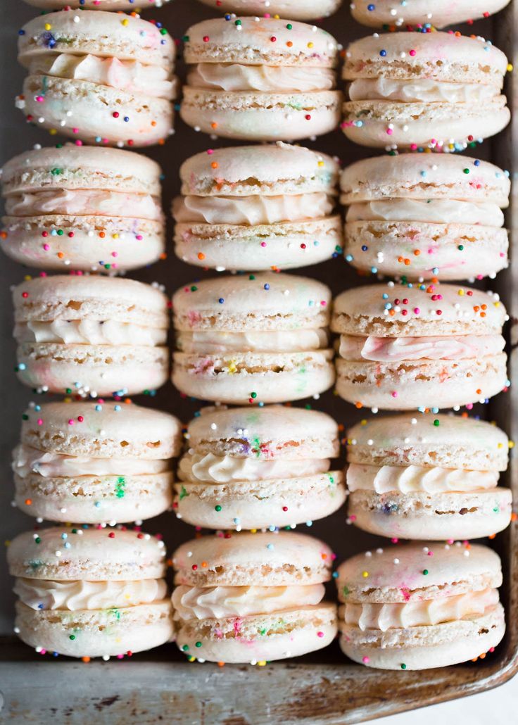 a pan filled with lots of white frosted donuts covered in sprinkles