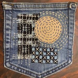 the back pocket of a pair of jeans with woven circles and squares on it, sitting on a wooden surface