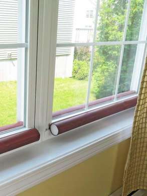 two windows in a house with grass and trees outside the window sill, one is closed