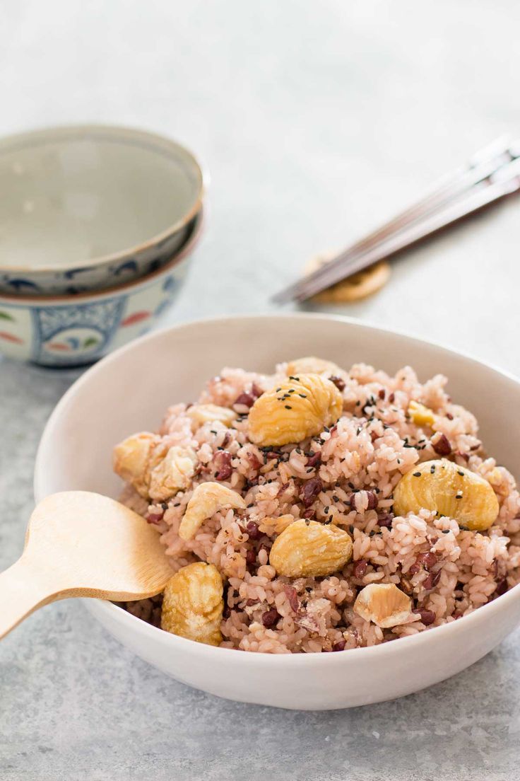 a white bowl filled with rice and nuts next to a spoon on a counter top