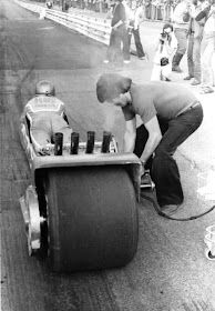 a man is working on a race car with an engine and some people watching from the sidelines