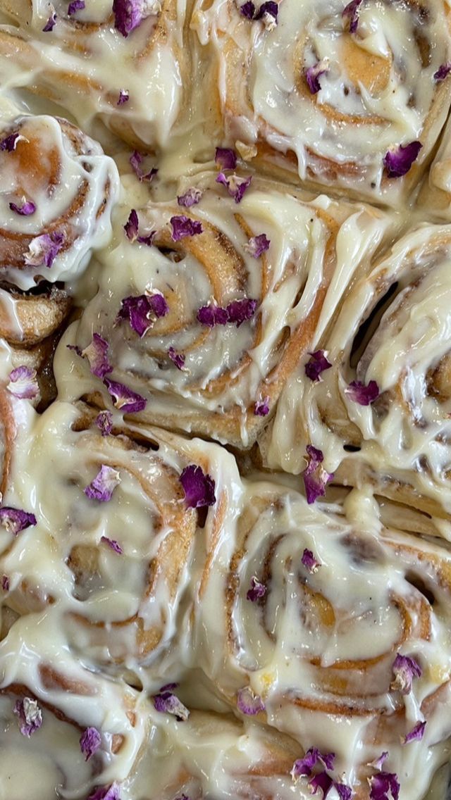 several rolls covered in white icing and purple flowers