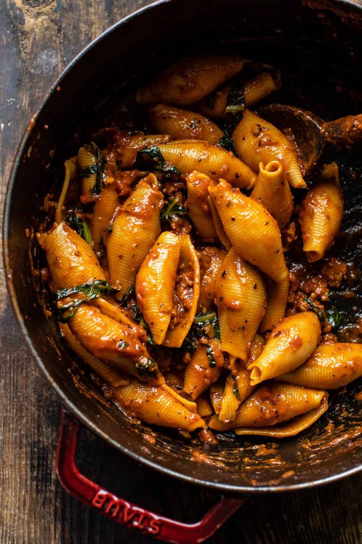 a pan filled with pasta and sauce on top of a wooden table