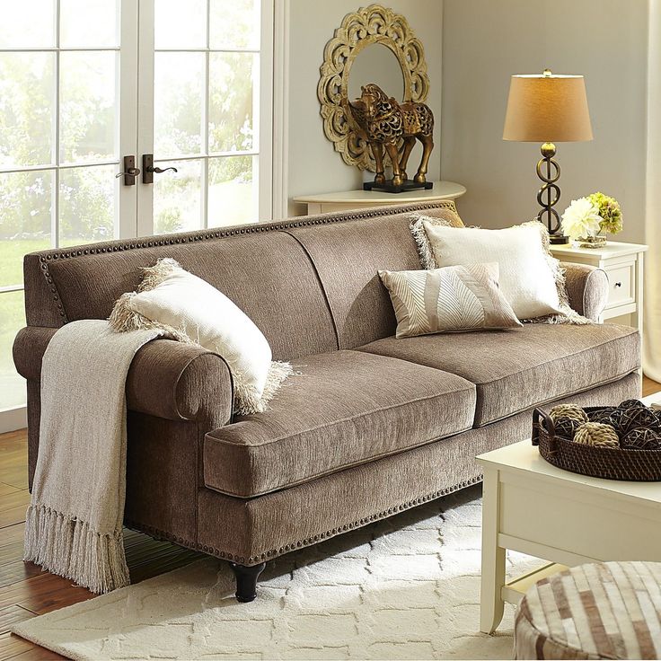 a living room scene with focus on the couch and pillows in front of the window