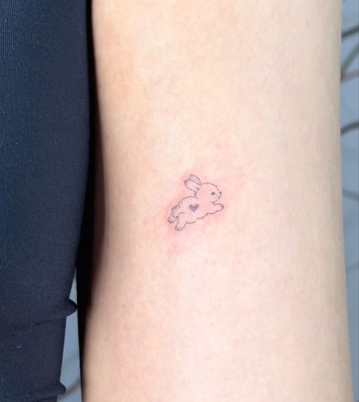 a small teddy bear tattoo on the back of a woman's left arm,