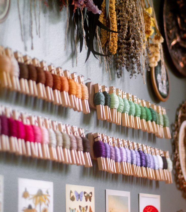 many different colored threads are hanging on the wall next to pictures and other items