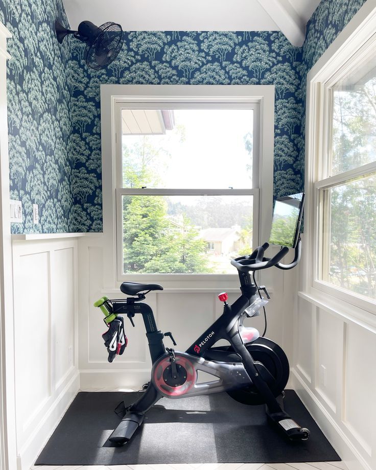 an exercise bike sits in the corner of a room with blue and white wallpaper