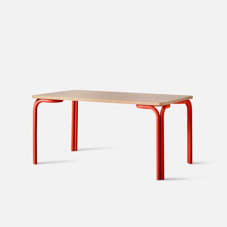 an orange table sitting on top of a white floor next to a wooden table with red legs