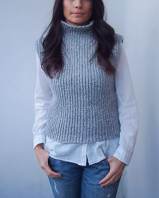 a woman standing in front of a white wall with her hands on her hips and looking at the camera