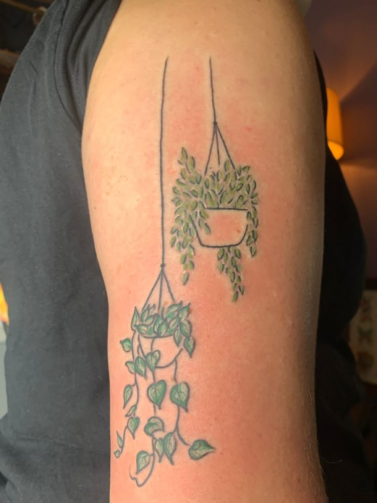 a man with a tattoo on his arm holding a potted plant hanging from it's side