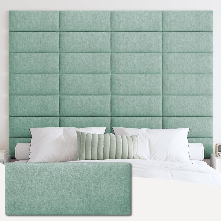 a green headboard on a bed with white sheets and pillows in front of it