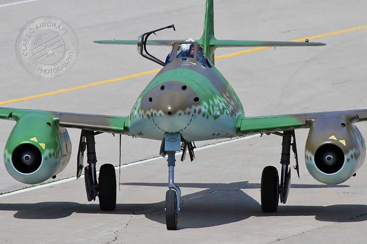 a small green airplane sitting on top of an airport runway