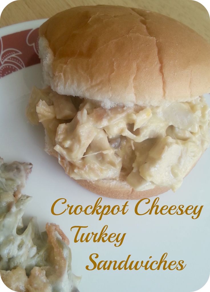 a close up of a sandwich on a plate with text overlay that reads crockpot cheesey turkey sandwiches