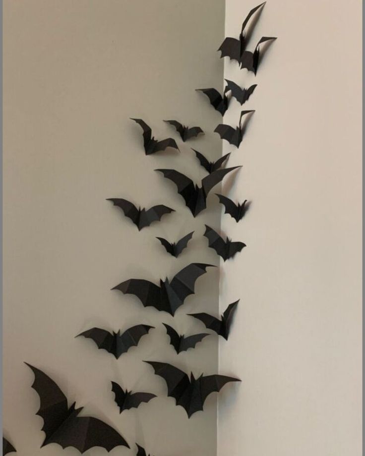 a group of bats hanging from the side of a wall in front of a white wall