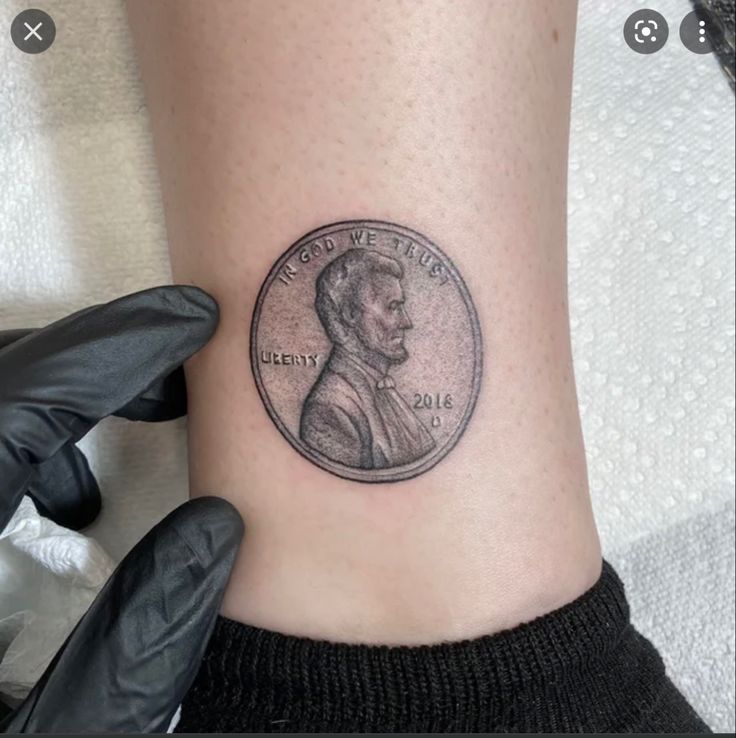 a woman's foot with a coin tattoo on it