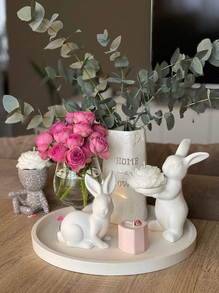 a vase with flowers and bunny figurines sitting on a table next to it