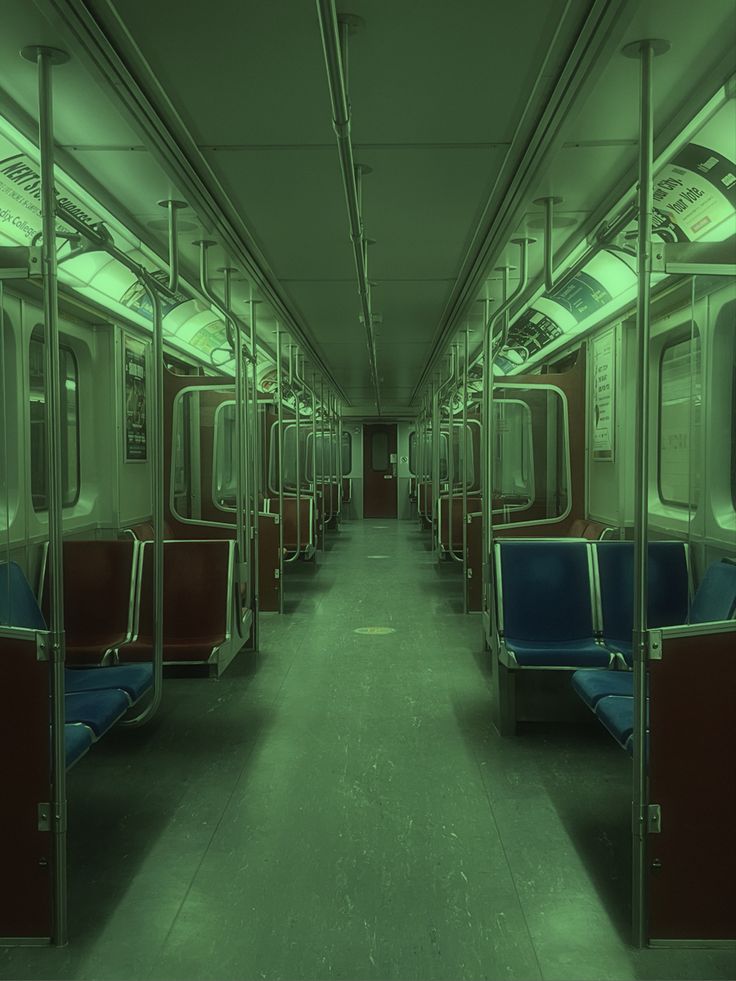 an empty subway car with blue seats and green lights on the ceiling, in a dark room