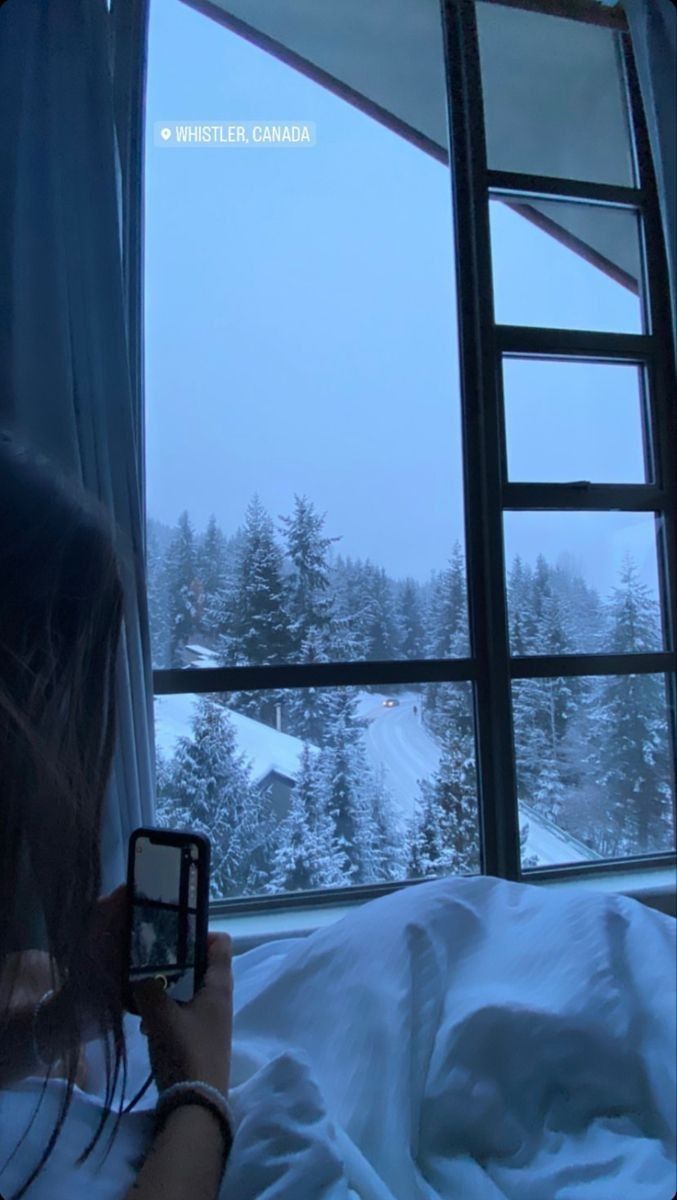 a woman taking a photo of the view from her bed in front of a window