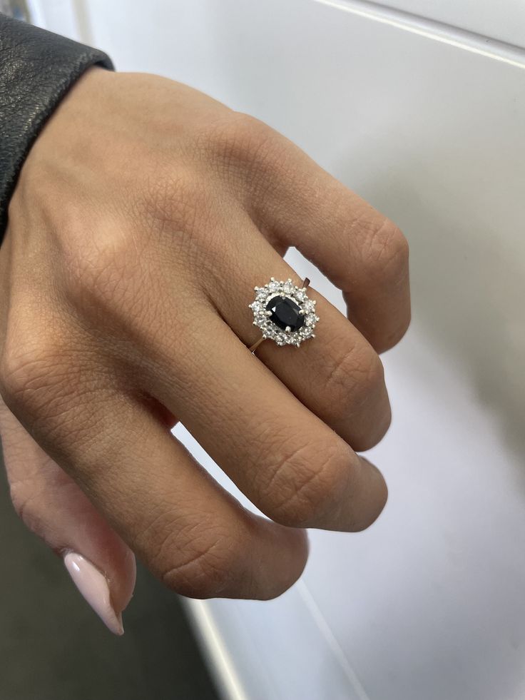 a woman's hand with a diamond and black stone ring on her left hand