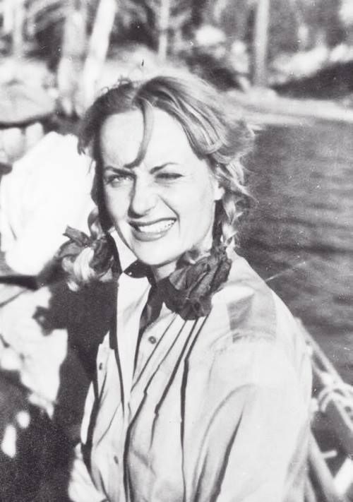 a black and white photo of a woman sitting in a boat smiling at the camera