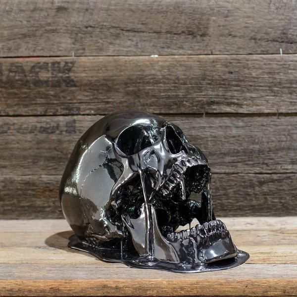 a metal skull sitting on top of a wooden table