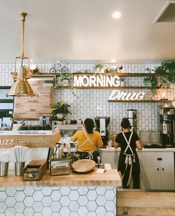 two people standing in front of a counter at a coffee shop, one person is ordering