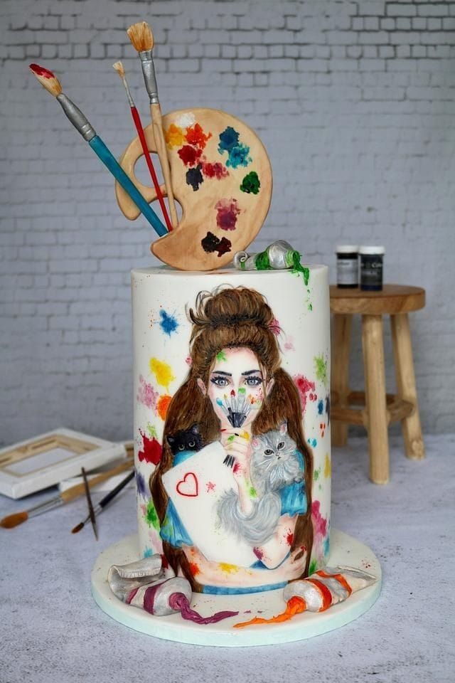 a cake decorated with an image of a woman's face and paintbrushes