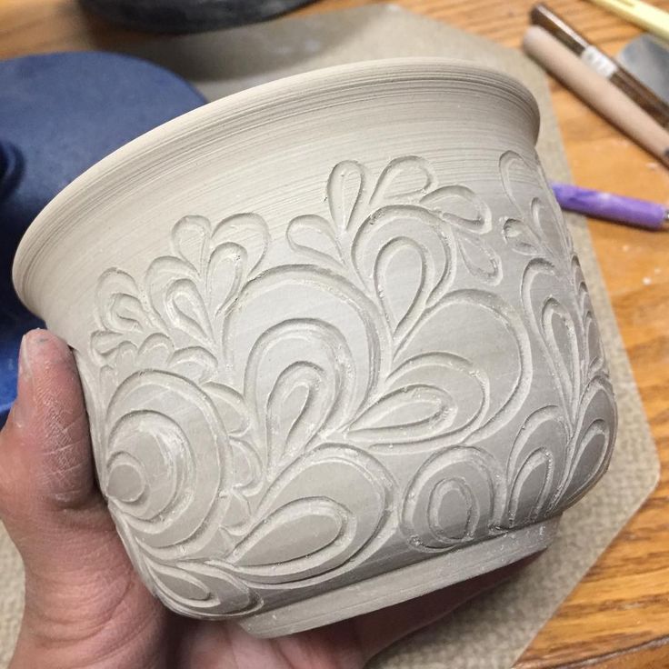 a person holding a white bowl on top of a wooden table