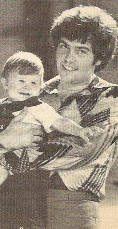 an old photo of a man holding a young boy in his arms and smiling at the camera