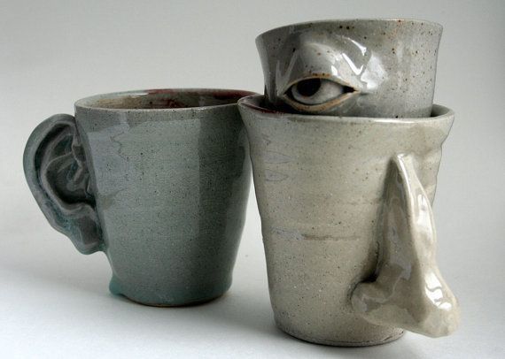 three ceramic cups sitting next to each other on a white surface with an eye in the cup