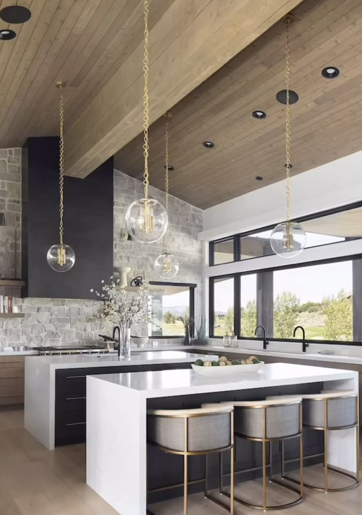 a large kitchen with an island and two stools in front of the counter top