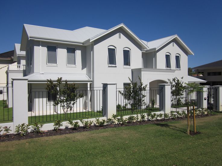 a large white house sitting on top of a lush green field next to a fence