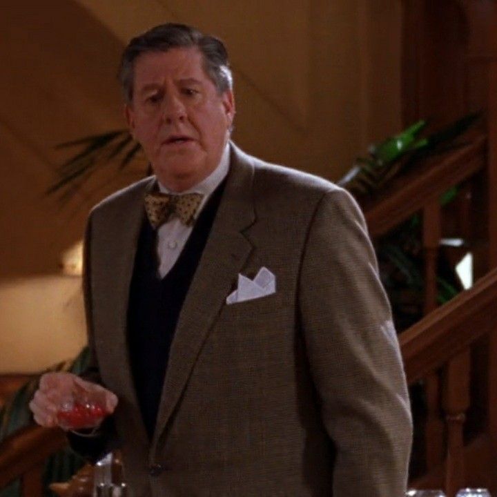 a man in a suit and bow tie holding a drink