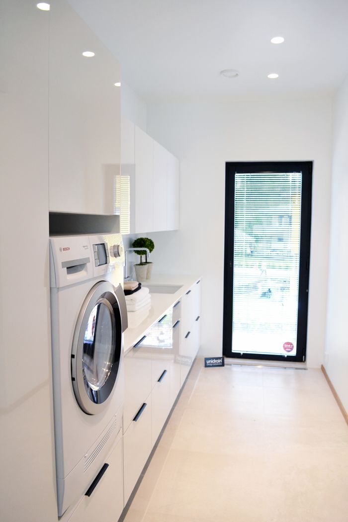 a washer and dryer in a room with white cabinets on the wall, next to an open door