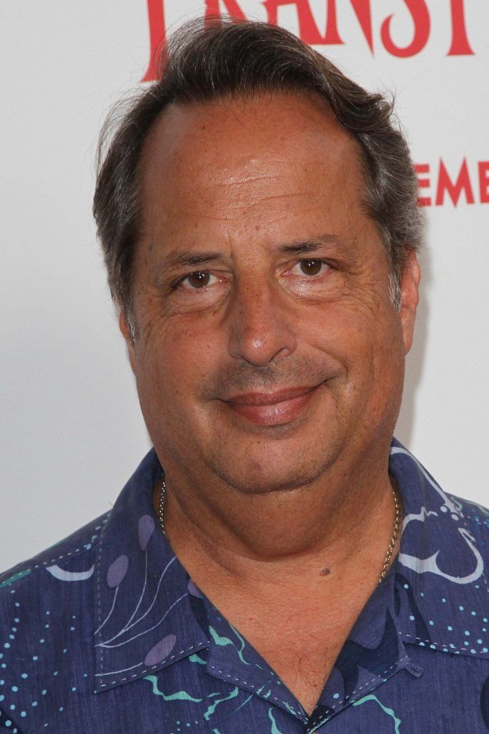 a close up of a person wearing a blue shirt and smiling at the camera with an intense look on his face