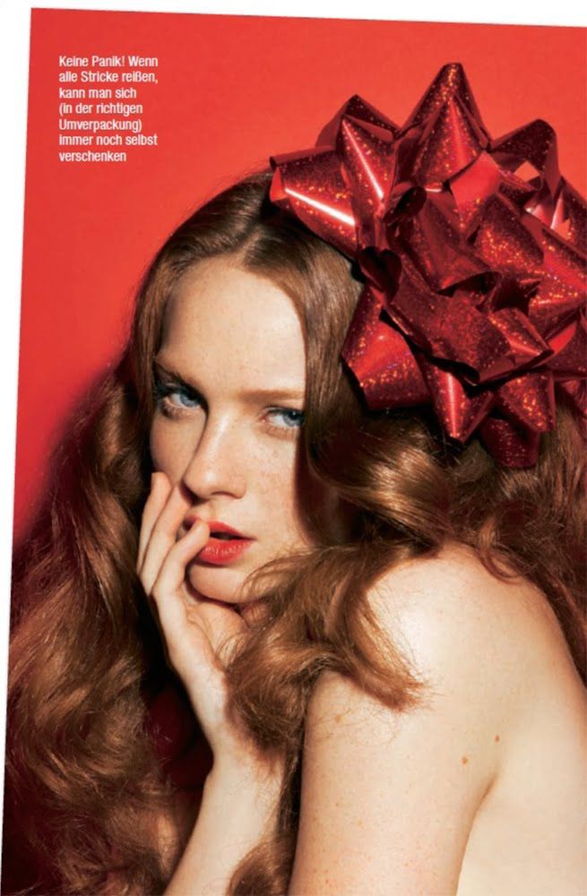 a woman with long red hair and a bow on her head is posing for the camera