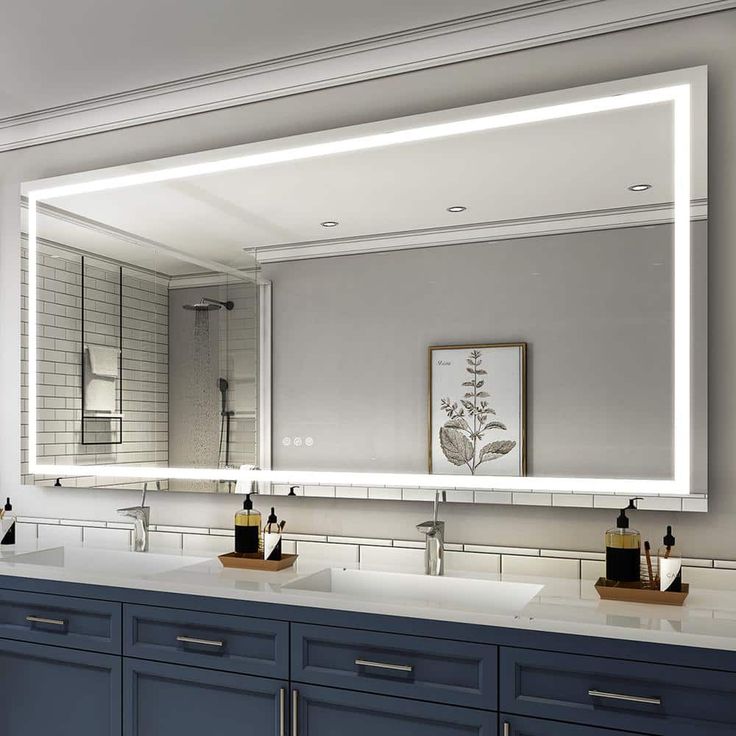 a bathroom vanity with two sinks and a large mirror above it that lights up the room