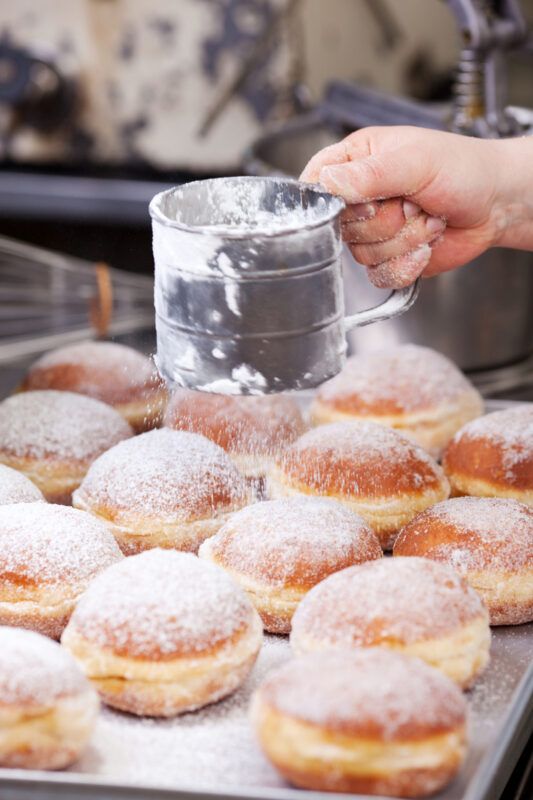 powdered donuts are being made on a conveyor belt