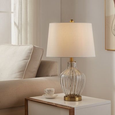 a table lamp sitting on top of a white box next to a couch in a living room