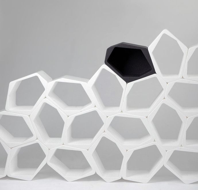 a white shelf with black hexagonal shapes on the top and bottom, in front of a gray background