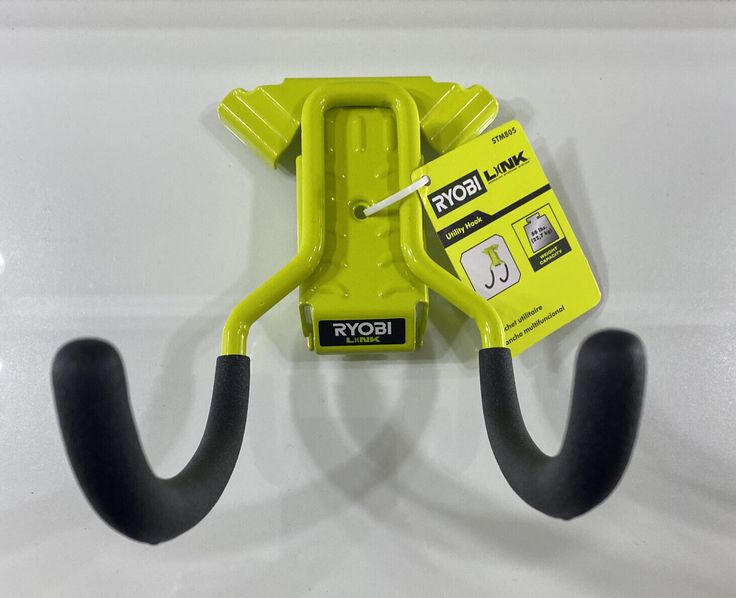 a yellow and black hook is attached to a white wall with two black hooks on it