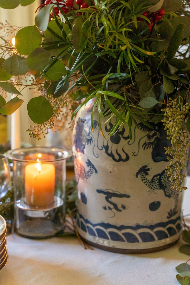 a vase filled with greenery and candles on top of a table