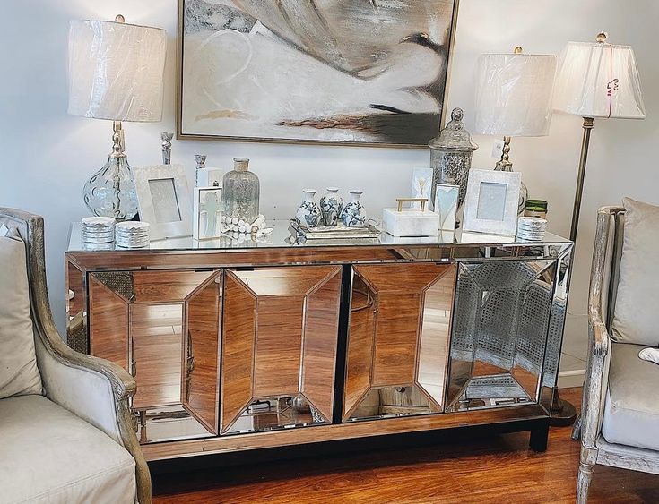 a living room with two chairs and a sideboard