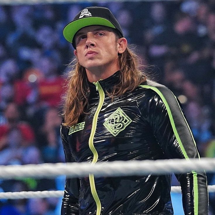 a man with long hair wearing a black wet suit and green hat standing in front of a net