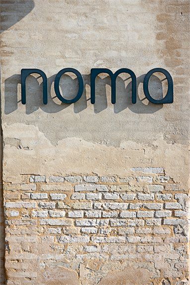 the word moma written in black on a brick wall