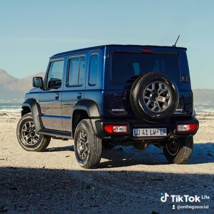 a blue jeep parked on top of a sandy beach