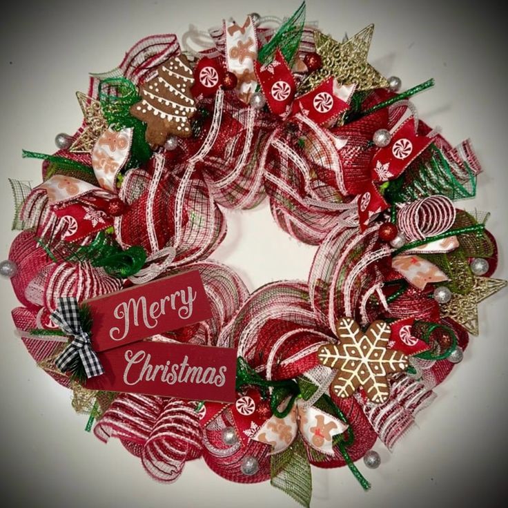 a red and green christmas wreath with merry decorations on the front, sitting on a white surface