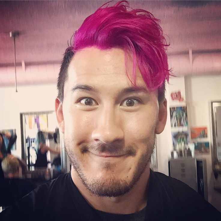 a man with pink hair is smiling at the camera